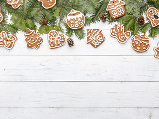 Christmas New Year's composition of spruce branches and homemade gingerbread on a white wooden table. View from above
