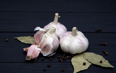 Close-up of garlic with spices on black wooden background.