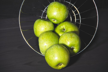 Green apples with water drops on black background.