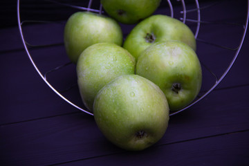Green apples with water drops on black background.