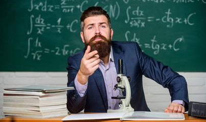 Educational conversation. Talking to students or pupils. School teacher concept. Teacher bearded man tell interesting story. Teacher charismatic hipster sit at table classroom chalkboard background