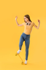 Fototapeta na wymiar Stylish hipster girl with skateboard on color background