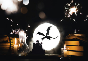 The silhouette of a fairy dragon attacks the magic Palace on the background of the full moon. Magic...