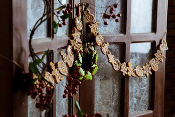 Beautiful Christmas gingerbread wreath and advent calendar hanging on a wooden window. Frosty glass pattern. Winter december day. New Year mood. Evening light