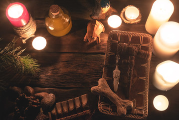 Witch doctor accessories in the light of burning candles on the wooden table background. The...