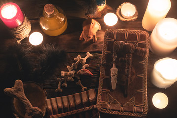 Witch doctor accessories in the light of burning candles on the wooden table background. The...