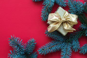 Red abstract Christmas background with golden Gift box and Christmas tree twigs