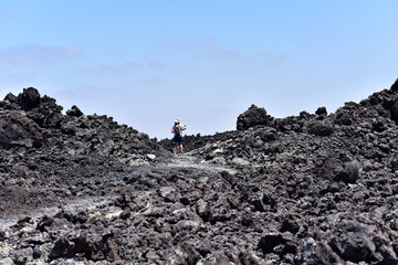 Tourists walking on the black lava fields in Timanfaya National Park, Lanzarote, Canary Islands, Spain