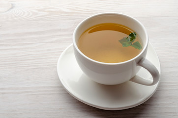 Cup and teapot of herbal tea with fresh mint on wooden boards