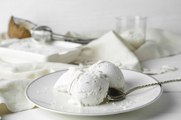 Plate with tasty coconut ice-cream on table