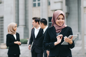 Portrait of cheerful happy businesswoman wearing black suit  standing  and holding tablet