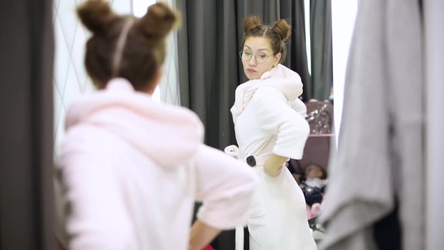 girl trying on a bathrobe in a clothing store. Examines himself in the mirror, deciding on a choice