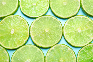 Fototapeta na wymiar Juicy fresh lime slices on light blue background, flat lay