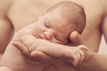 Newborn baby sleeping in daddy's hands