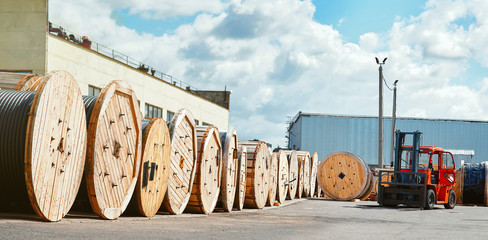 Reels with electrical power cables at the supplier’s warehouse. Wire on wooden coils. Forklift on...