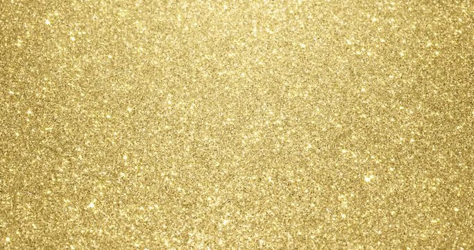 Gold glitter background with sparkling texture. Golden shimmering light, stars sequins sparks and glittering glow foil background