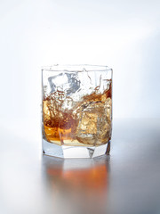 splash of whiskey with ice osolated on white