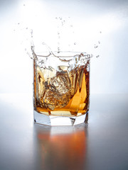 splash of whiskey with ice osolated on white