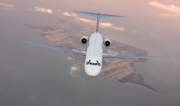 Passenger jet flying at a high altitude over an island 
