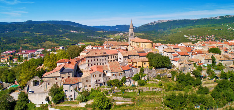 Buzet. Hill town of Buzet surrounded by stone walls in green landscape aerial panoramic view