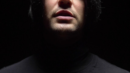 closeup. male mouth with crooked teeth screaming. Black background.