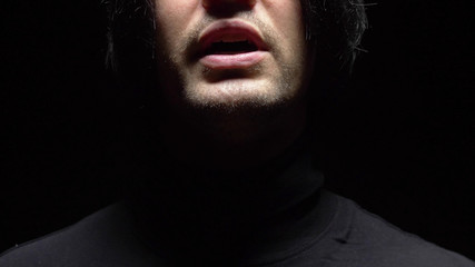 closeup. male mouth with crooked teeth screaming. Black background.