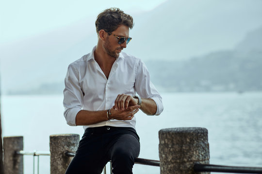 Stylish man in white shirt checking the time over the mountains background - Powered by Adobe
