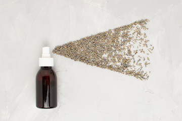 Transparent cosmetic amber glass spray bottle on a white background. Lavender flowers scatter like small droplets from a spray. flat lay