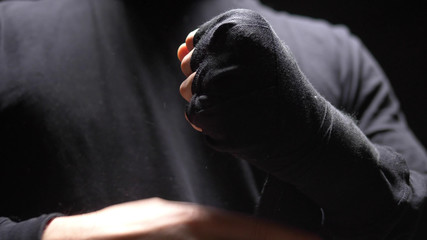 closeup. male hands wrapped around a black elastic bandage on hand.