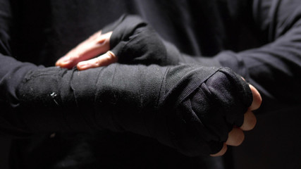 closeup. male hands wrapped around a black elastic bandage on hand.