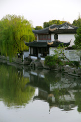 Fototapeta na wymiar Classical houses in Jiangnan, China. The white walls and black tiles are matched with green weeping willows. The reflection of the river reflects the poetic and picturesque scenery.
