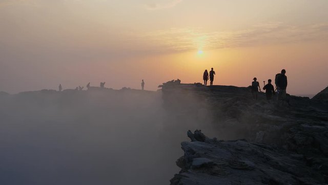 Full shot of people hiking on Dallol volcano covered with smoke coming from its crater.