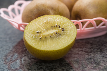 Some kiwis are served in a pink fruit basket