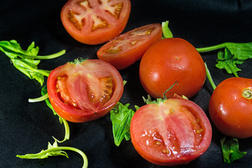 Cut tomatoes and vegetables on a black linen background
