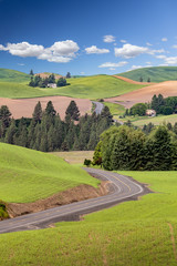 A highway cuts through farms among the rolling hills of Palouse in Washington state, USA