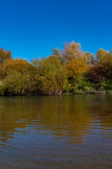 Autumn landscape with river Raba trees and blue sky.