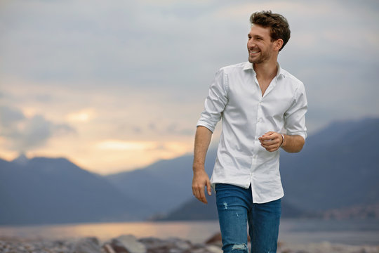 Smiling Male Model Standing On A Background Of Lake And Mountains