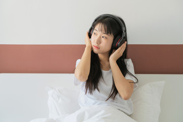 asian young woman listen to music headphone on bed