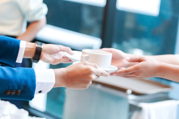 Hand barista hold cup of coffee and send to hands businessman.