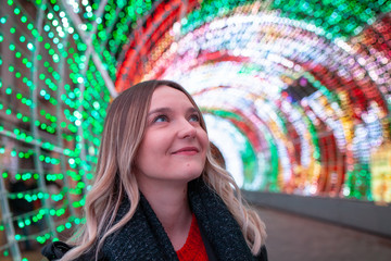 Young beautiful caucasian girl looking at Christmas lights in the street