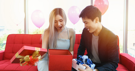 Asian couple lover are giving a gift box with Christmas gift in Christmas holiday and happy new year patty
