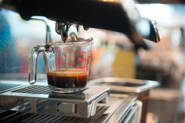 Coffee in measuring cup on a coffee machine