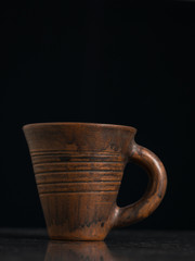 Clay mug with handle on black background.