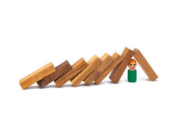 A wooden toy of a boy lies under a large number of obstacles in the form of wooden blocks on a white isolated background. The concept of overcoming difficulties and life hardships