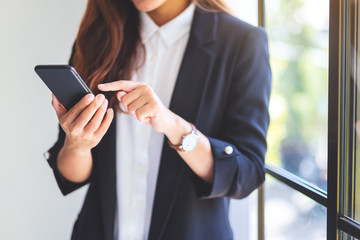 Closeup image of a businesswoman holding and using mobile phone