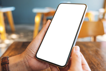 Mockup image of hands holding black mobile phone with blank desktop screen