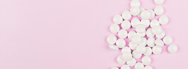 White pills on a pastel pink background. Flat lay, top view, overhead, mockup, template, copy space. Pharmacy and medical concept