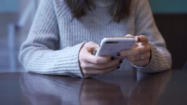 Woman on cell phone in restaurant texting and looking at social media in public