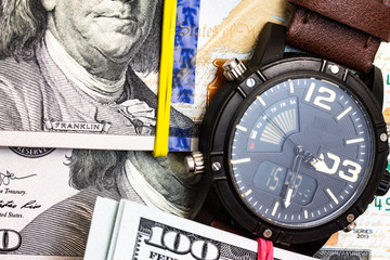 Closeup of modern hand watch lying on background made from one hundred dollar notes