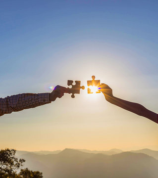 Human hands holding jigsaw puzzle at sunset background.team work and success and strategy concept.